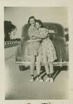 Unidentified women hugging in front of a car
