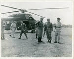 Military officials standing by helicopter. by Author Unknown