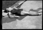 Female sunbathing at a pool laying on her back by J. R. Cofield