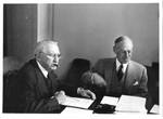 Unidentified men sitting at conference table. by Life