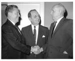 Felton M. Johnston between two men shaking hands. by Author Unknown