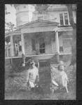 Two children in front of house. by Author Unknown