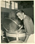 Farrington High School swtudent stirring hot food in a steam jacketed kettle.