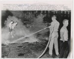 Firemen attempt to extinguish burning cross by Edward Movitz