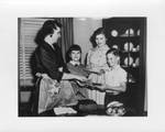 Mrs. Eastland serving the cake to Sue, Ann, and Woods in the dining room. by Author Unknown