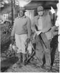Eastland with gun and African-American holding a number of quail in each hand. by Author Unknown