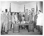 Eastland seated in his congressional office with an unidentified group of men standing behind him by Author Unknown