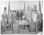 Eastland sitting at desk with Bolivar County Planters Club standing behind him. by Author Unknown