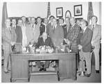 Eastland siting at a desk with the Bolivar County Planters Club standing behind him. by Author Unknown