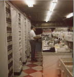 John Leslie behind the counter of Leslie Drugstore. by Author Unknown