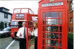 John Leslie and woman in front of double decker tour bus and phone box, image 003 by Author Unknown