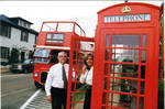 John Leslie and woman in front of double decker tour bus and phone box, image 004 by Author Unknown