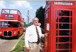 John Leslie and woman in front of double decker tour bus and phone box, image 002 by Author Unknown