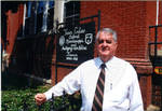 John Leslie in front of the Sister Cities Aubigny-sur-Nere, France, and Oxford, Mississippi sign at City Hall. by Author Unknown