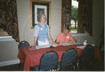 Two women behind table by Author Unknown
