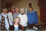 Group of people standing around sitting blond woman, image 1 by Author Unknown
