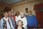 Group of people standing around sitting blond woman, image 2 by Author Unknown