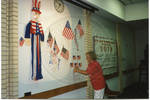 Woman taping flag to wall by Author Unknown