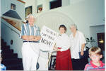 Two women and man standing with 'Women's Suffrage NOW!' sign by Author Unknown
