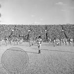 Marching band on field during football game by Edwin E. Meek
