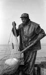 African American man with fishing gear on boat by Edwin E. Meek