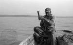 African American man fixing hook on boat by Edwin E. Meek