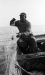 African American man with fishing net on boat by Edwin E. Meek