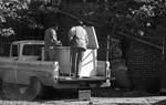 Two men on bed of pickup truck with large cooler by Edwin E. Meek