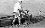 Man loading boat with fishing gear by Edwin E. Meek
