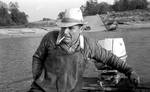 White man in fishing boat with cigarette by Edwin E. Meek