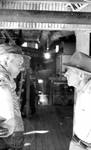 Two white men talking inside cotton processing building by Edwin E. Meek