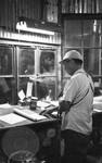 White man at desk at cotton processing building by Edwin E. Meek