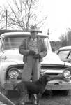 Man with hunting dog stand in front of a truck by Edwin E. Meek