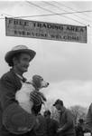 Man holding beagle under trade day sign: Image 1 by Edwin E. Meek