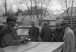 Men standing around cars by Edwin E. Meek