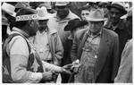 Native Amenrican man (Choctaw) in regalia sells medicine to crowd of men: Image 17 by Edwin E. Meek