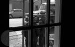 Two white men standing on street, seen through window by Edwin E. Meek