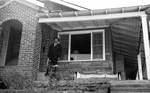 African American man standing on house porch by Edwin E. Meek