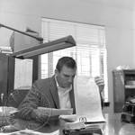 Charles Flowers seated at desk: Image 1 by Edwin E. Meek