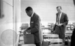 James Meredith standing with briefcase in class by Edwin E. Meek