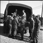 Seven National Guardsmen taking supplies off a truck. by William T. Miles