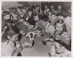 Cafeteria scene with elementary age children having soup and milk for lunch. by USDA