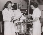 The power mixer. Violet Brooks, laboratory assistant, aids Vera Brastow, Food Specialist, in the development of a recipe for 100 using the power mixer. School Lunch Recipe Laboratory, Bureau of Human Nutrition and Home Economics, Agricultural Research Center, Beltsville, Maryland.