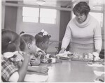 This is one of a series of photographs from Picture Story 217 "New Food Program is First to Feed Pre-School Youngsters", which tells how the U. S. Department of Agriculture is providing food and cash help to needy pre-school children. Children at the Alerding Settlement House in Gary, Indiana are being served a mid-morning snack of do-nuts and milk on November 1, 1968. Funds from the new program will also supply food for their lunches. (Youngsters at day-care centers in Gary, Indiana were the first in the nation to benefit from a new USDA child food service program. Hailed as a "new dimension" in child nutrition, the program provides cash and USDA donated foods to public and private non-profit agencies to help them provide nutritious meals to children in day-care and similar organized activities, and in summer recreation and day camps. Emphasis is on getting food service into activities in low-income areas, and in neighborhoods with high percentages of working mothers.) by USDA