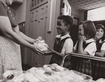 SCHOOL LUNCH, Serving United States Department of Agriculture Office of Information USDA's Food and Nutrition Service has worked with the Catholic Arch Diosese [sic] of Philadelphia to bring about this in flight type hot lunch being served here at Sr. Anthony de Padua parochial school. Here volunteer mother serves the hot lunches to eager students.