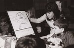 Mrs. Janice Gray, a third grade teacher at Arcola Elementary School and her pupil, Leon Goza, 8, show his award-winning poster to his fellow students during lunch in the school cafeteria. Leon's poster will be exhibited at the Montgomery Mall Shopping Center, January 29 through February 3, 1973, as part of a U.S. Department of Agriculture sponsored exhibit, "Agriculture Days on the Mall." Silver Spring, Maryland. by USDA