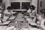 The Jemez Valley School staff serves food through an open window at the end of the serving line. New Mexico. by USDA